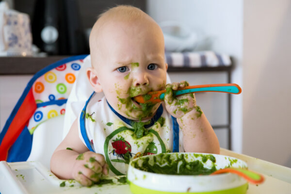 Messy baby eating green food