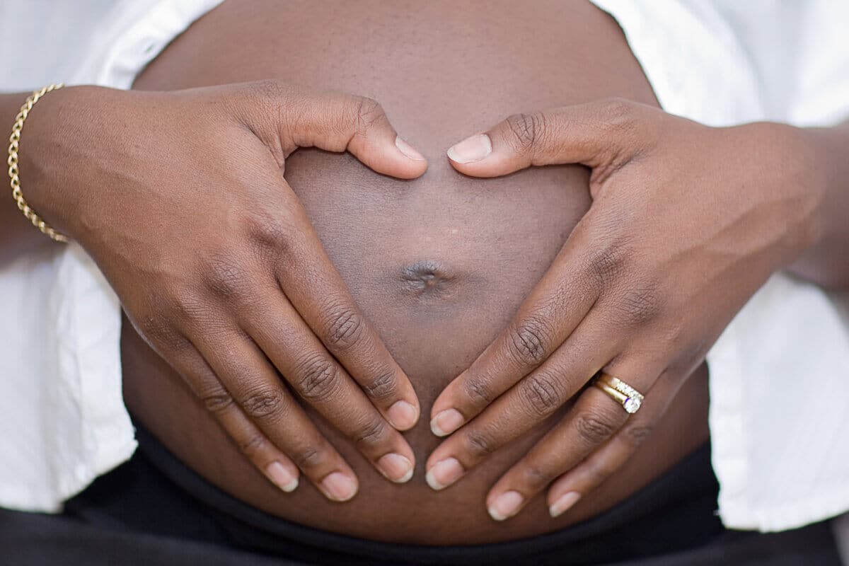 Pregnant woman makes a heart with her hands over her belly