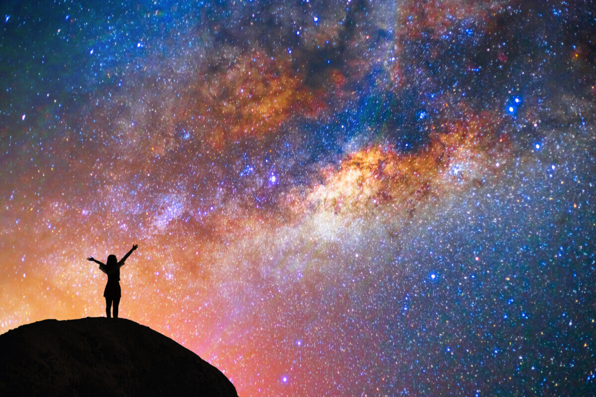 Girl with arms raised at starry night