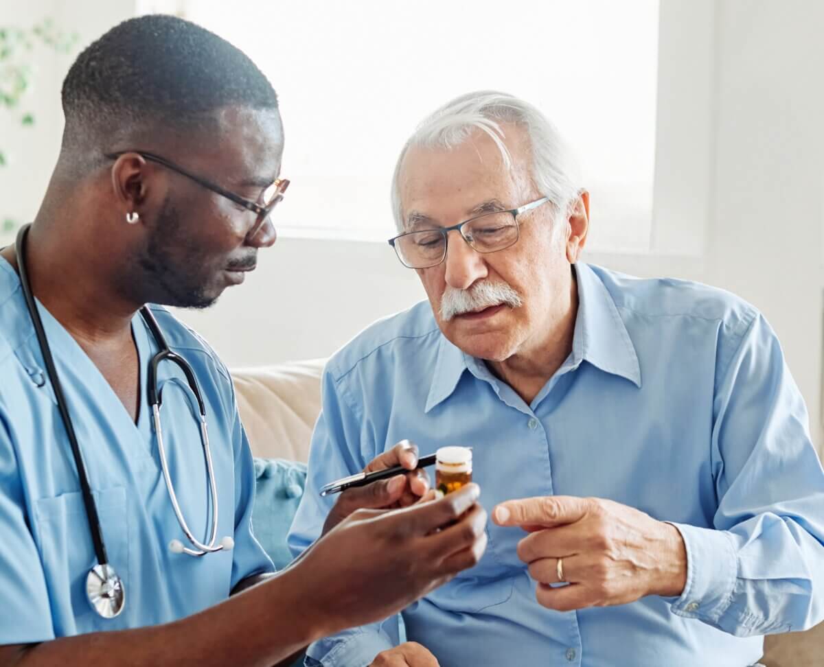 Caregiver giving old man medication in a nursing home