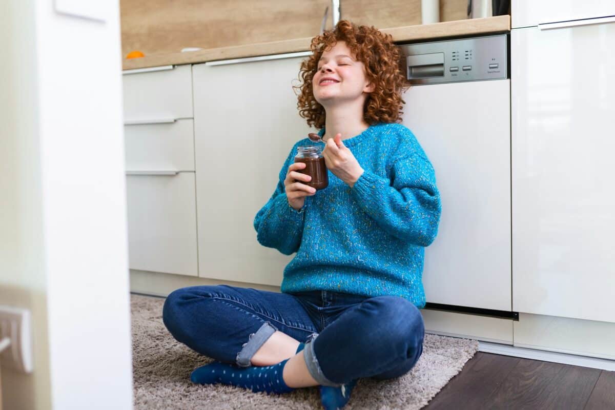 Woman joyfully eating chocolate in the kitchen