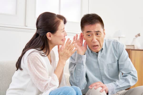 Woman yells into her husband's ear because of hearing loss