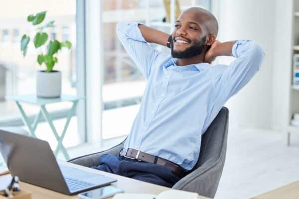 Happy man sitting back in office chair relaxing