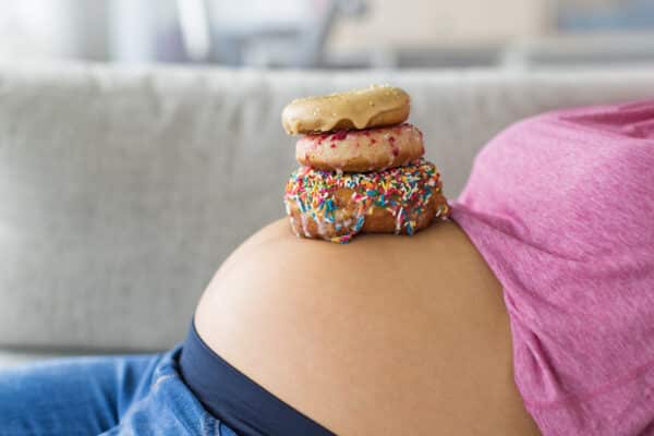 Pregnant woman with donuts on belly: Junk food pregnancy cravings