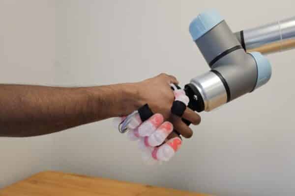 A robotic hand and human hand in a handshake