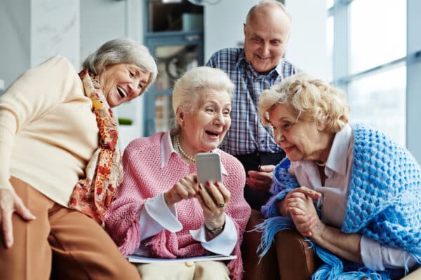 Four seniors looking at a mobile phone