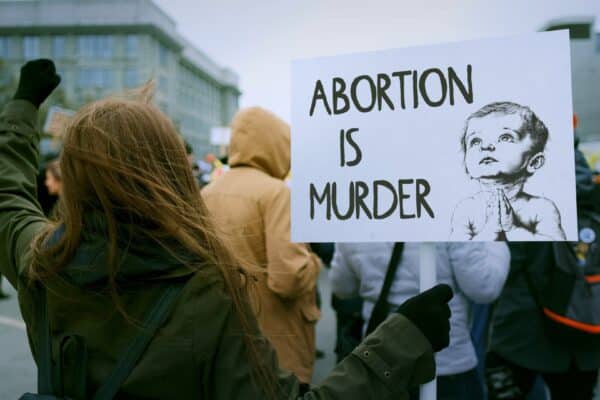 A pro-life supporter protesting with "abortion is murder" sign