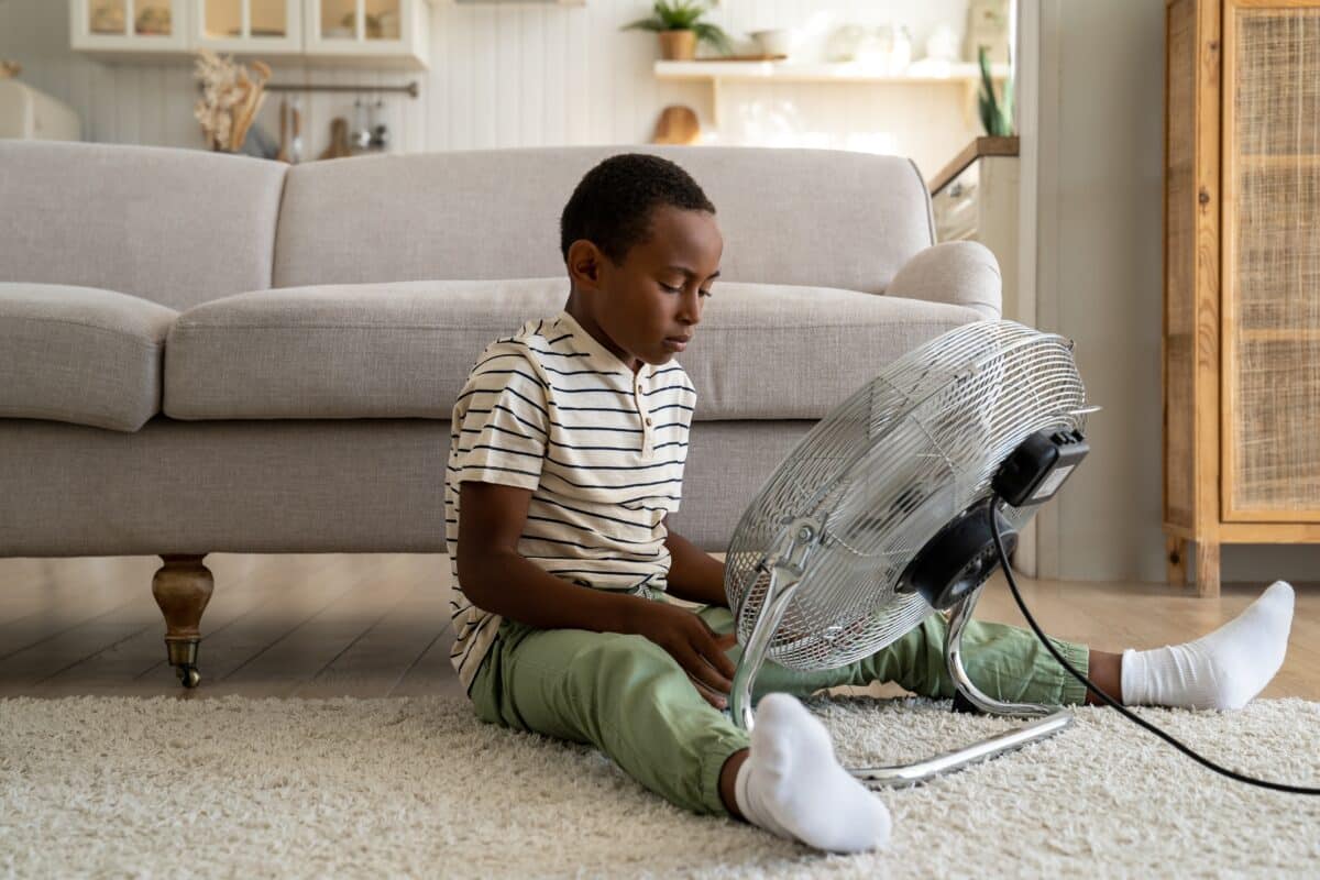 Boy sitting in front of fan in hot house with no air conditioning