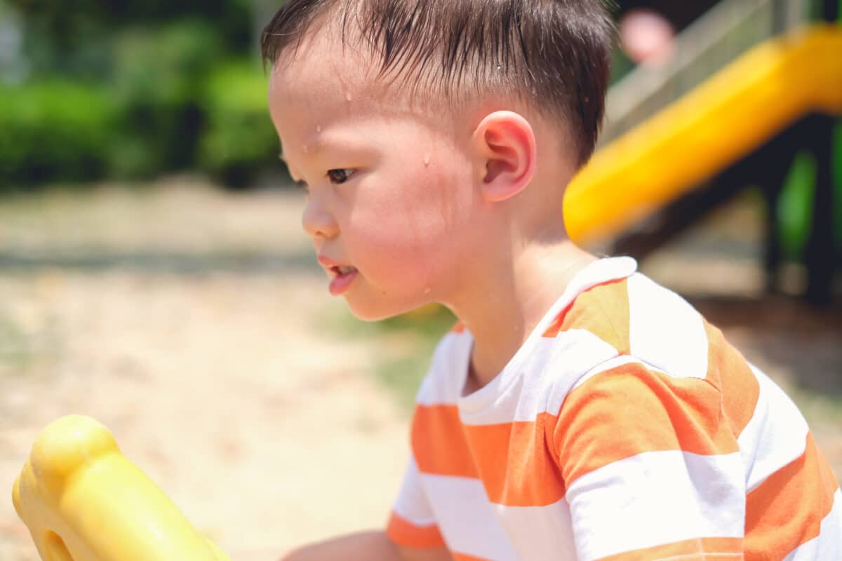 Child sweating in hot summer heat outside