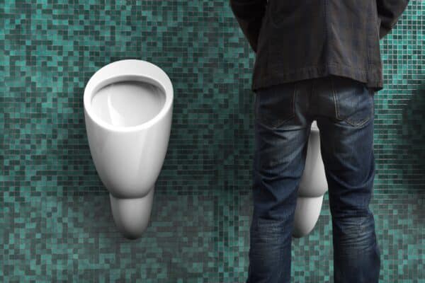 Man peeing in a urinal in a public bathroom
