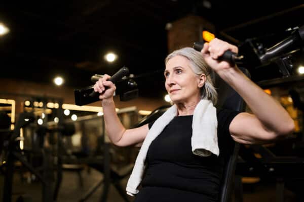 Older woman doing shoulder press exercise at gym