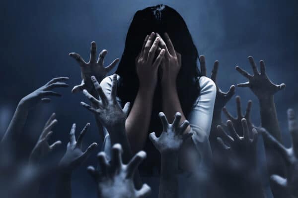 Woman surrounded by scary hands