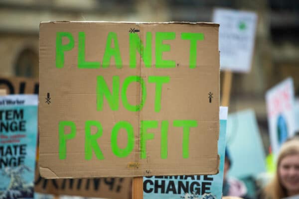 Climate change protester holds sign that reads, "Planet Not Profit"