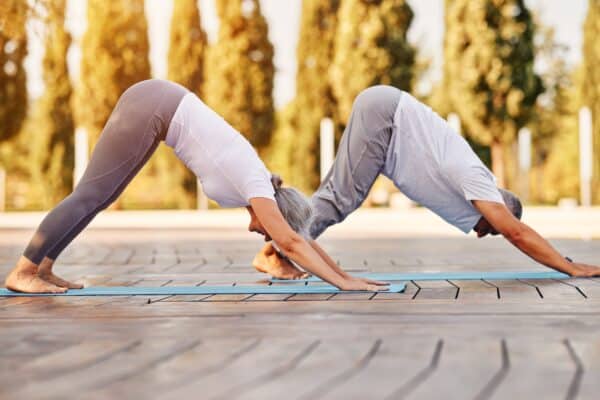 Older couple in downward dog pose practicing yoga