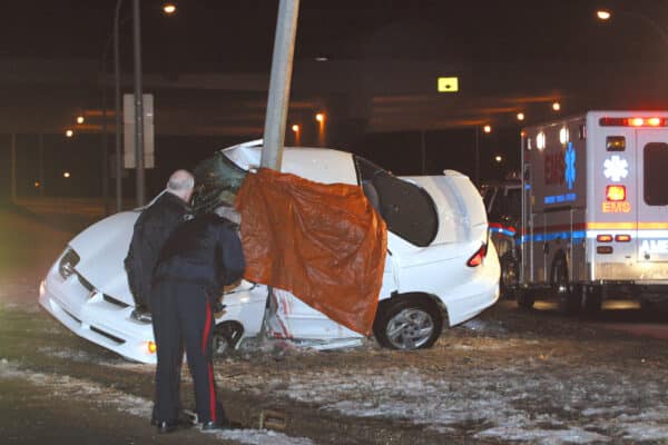 Police and paramedics tend to a deadly car accident.