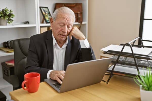 Older senior working at his desk bored