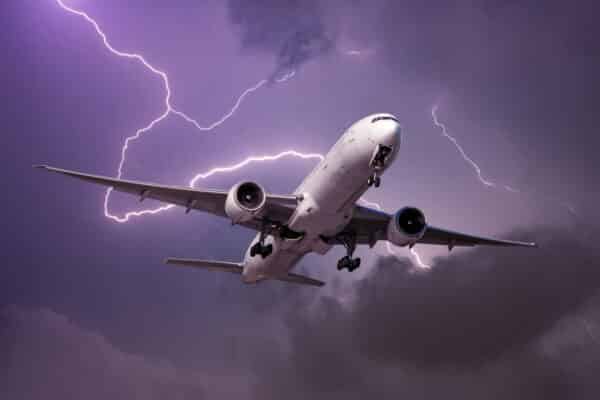 Landing airplane during a strong wind in a storm against the backdrop of a flash of lightning