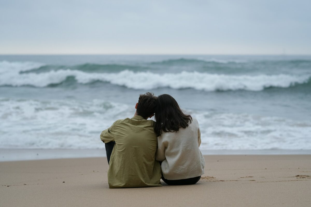 Couple on beach watching sunrise or sunset