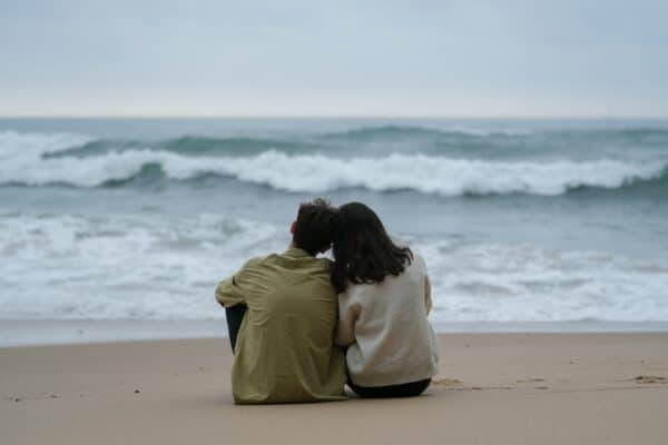 Couple on beach watching sunrise or sunset