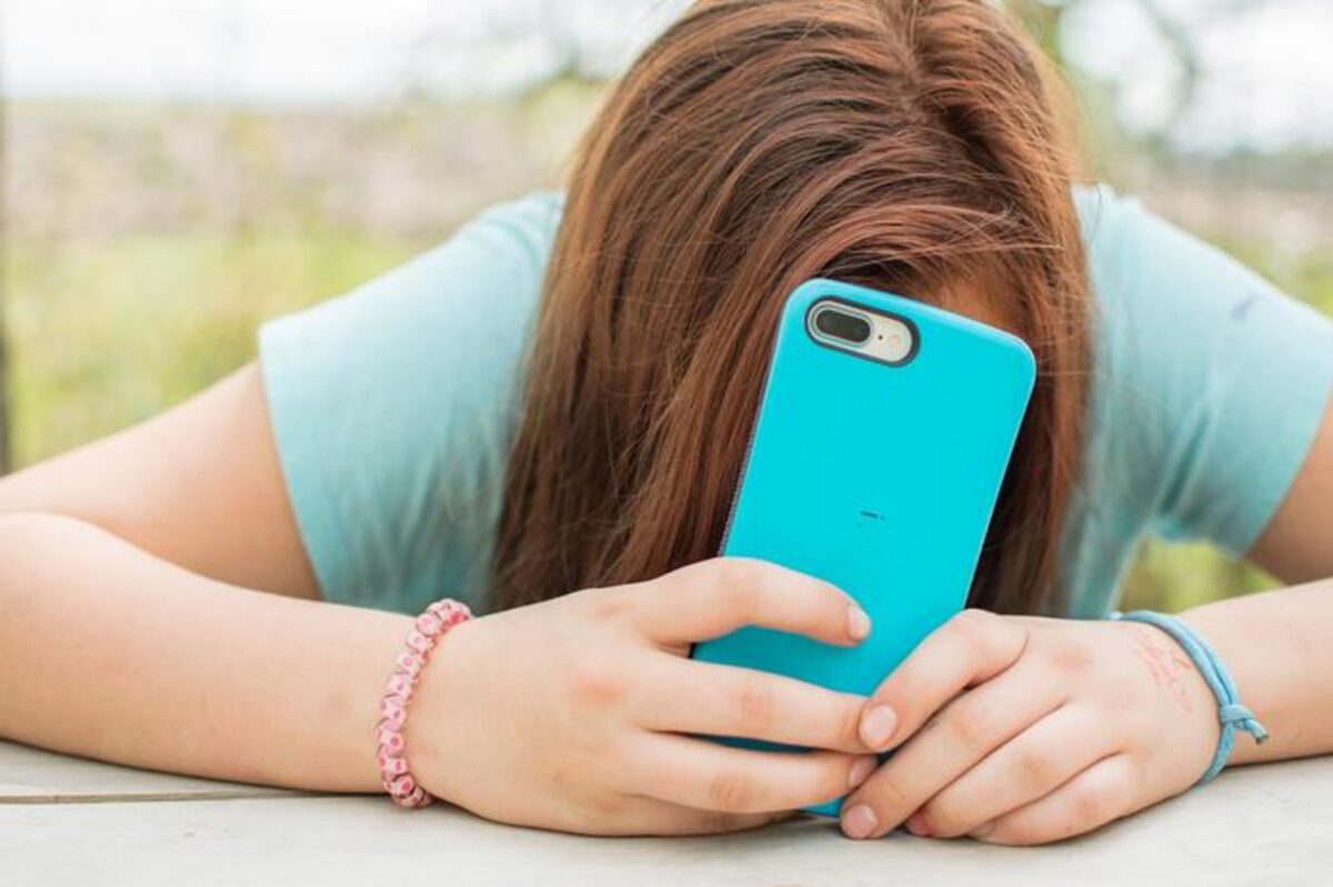 Teen covering face with phone