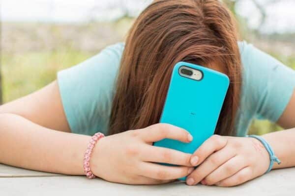 Teen covering face with phone