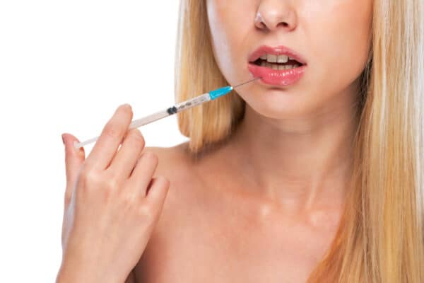 A teenager holding up a lip filler syringe