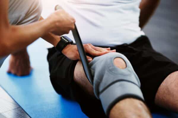 Therapist wrapping knee brace on patient