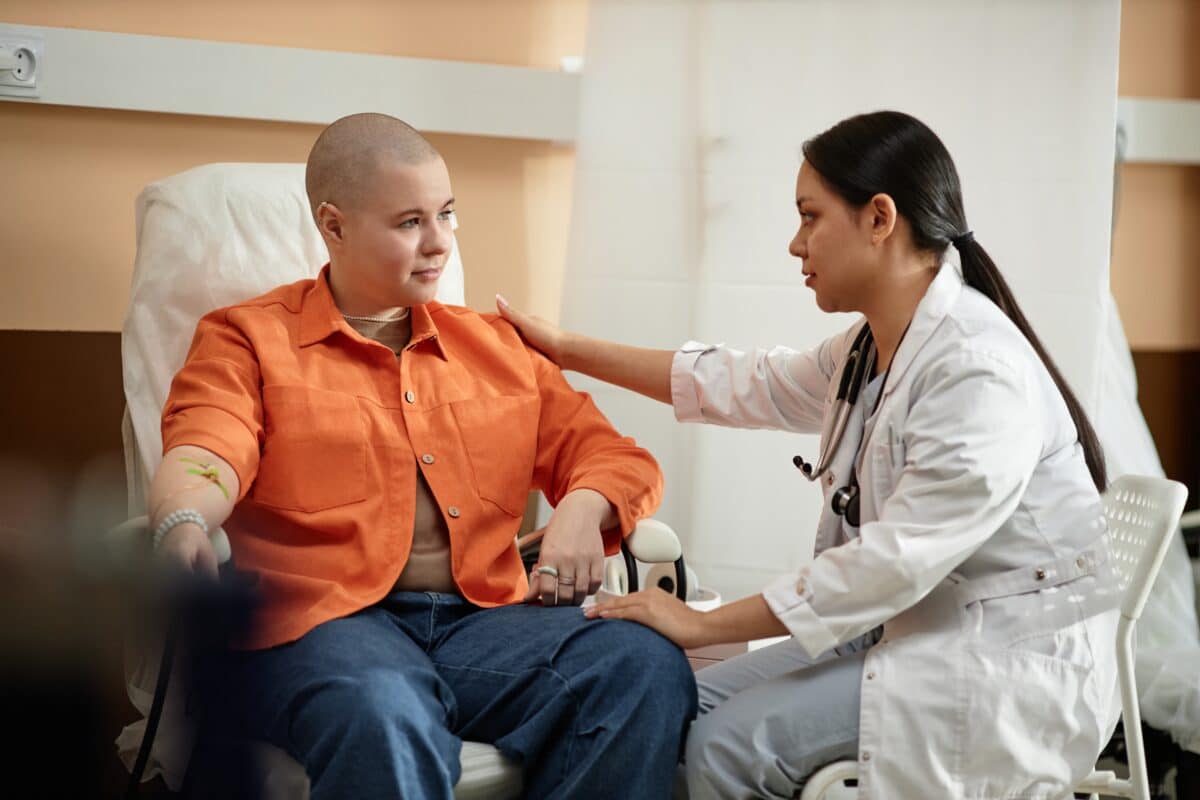 A nurse comforting a cancer patient receiving chemotherapy treatment in hospital.