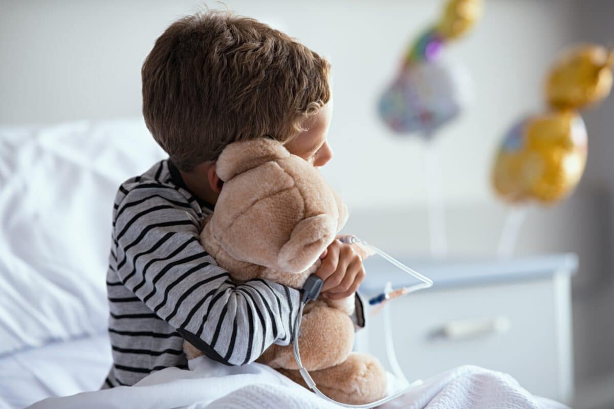 Child patient in hospital hugging a teddy bear