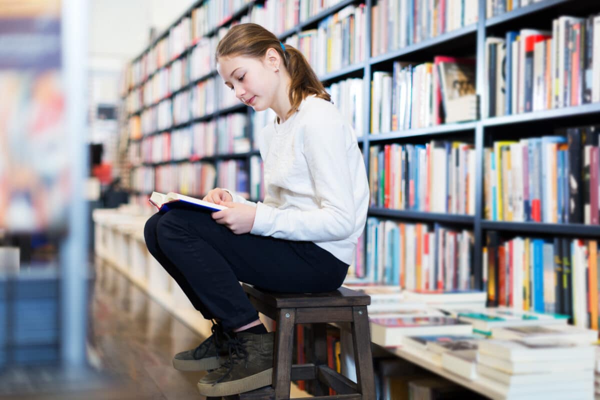 Child reading book in library