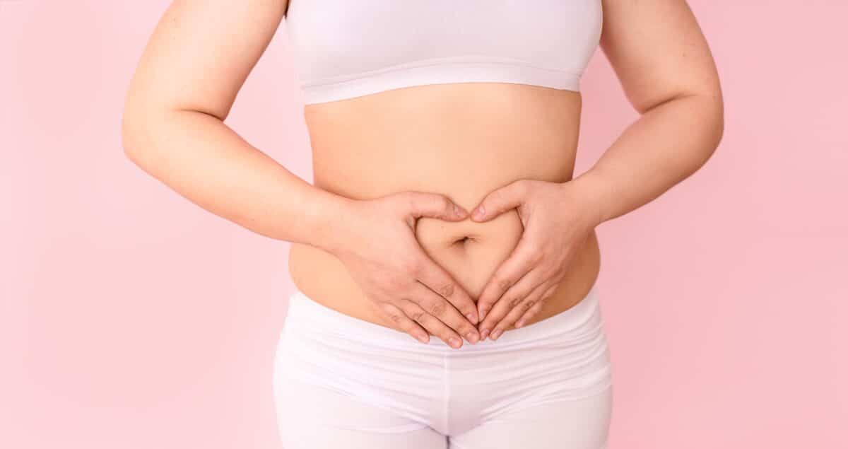 Woman making a heart with her hands over her belly and gut