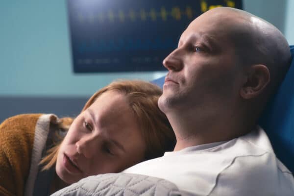 A cancer patient is comforted by his wife while receiving treatment