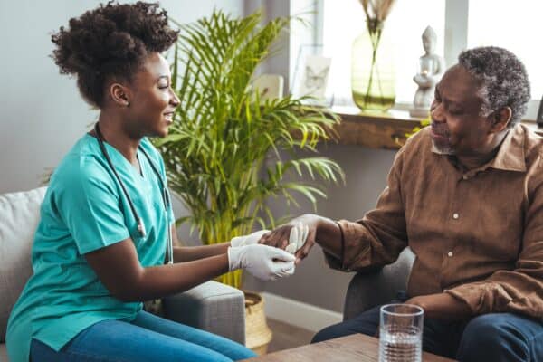 A nurse comforts an elderly patient, holding his hand