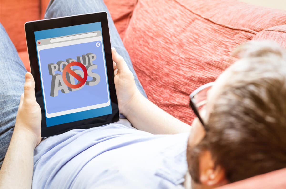 Man using an ad blocker to block popup ads on his tablet