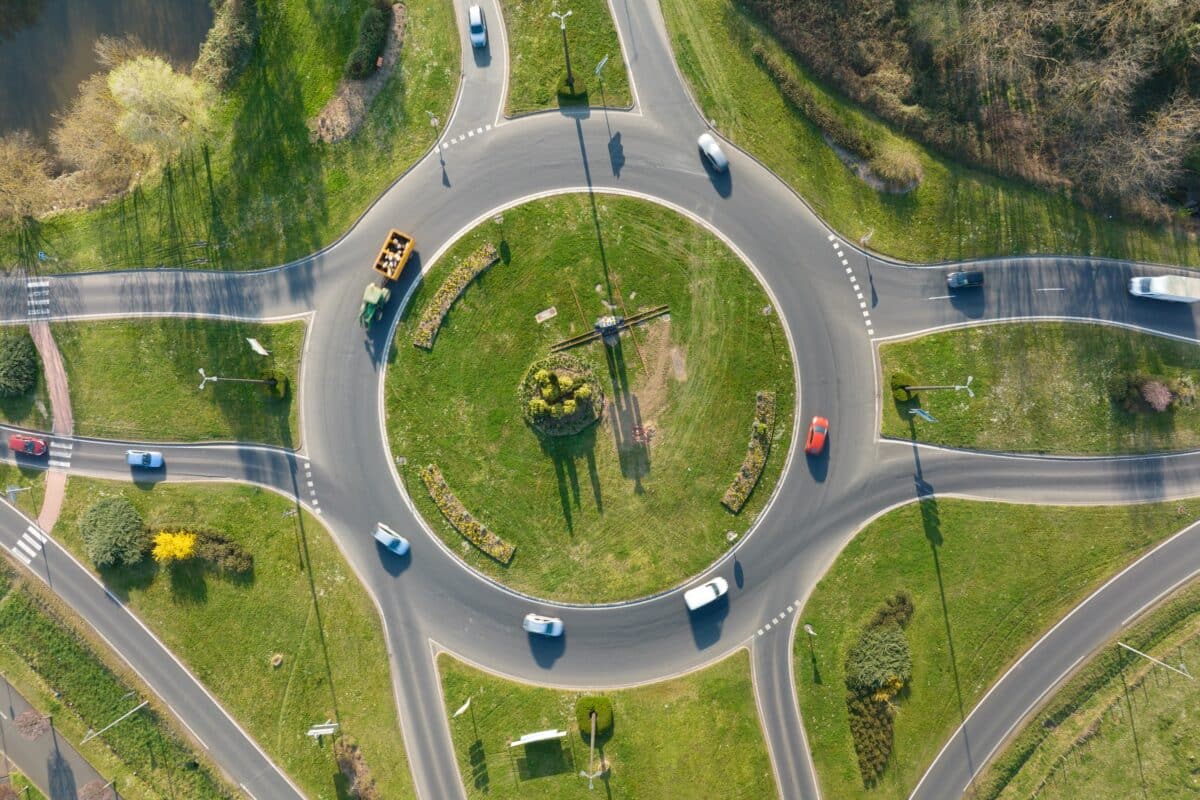 Aerial view of road roundabout (traffic circle) intersection with moving heavy traffic.