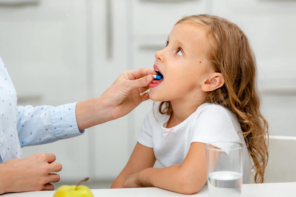 Parent giving her young child a prescription drug pill