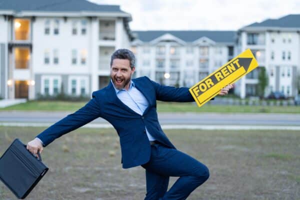 Excited business man holding a "For Rent" sign