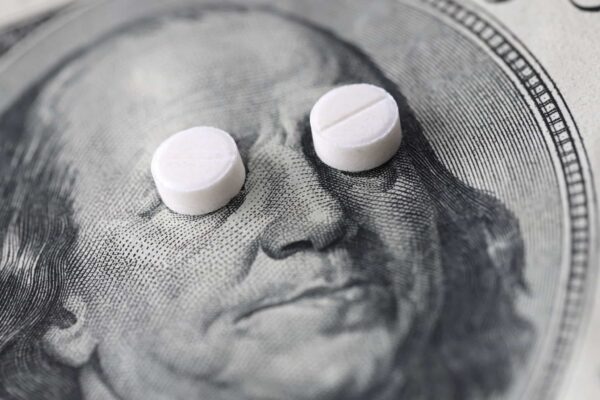 Big Pharma payments concept: Pills cover Ben Franklin's eyes on a $100 bill