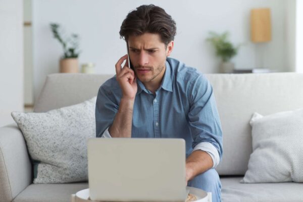 A man working remotely from home on a business call with his laptop opened