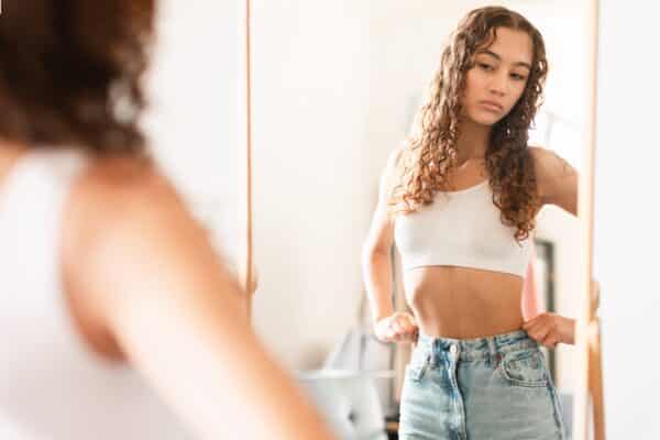 A teen girl looks at herself in the mirror