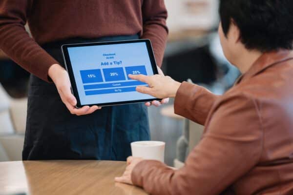 Server holds the screen for the customer to leave a tip.