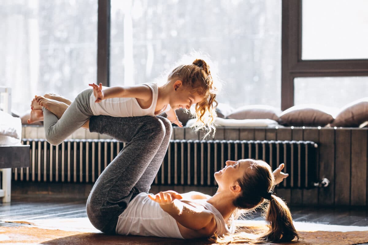 A mother and her child doing yoga and playing at home