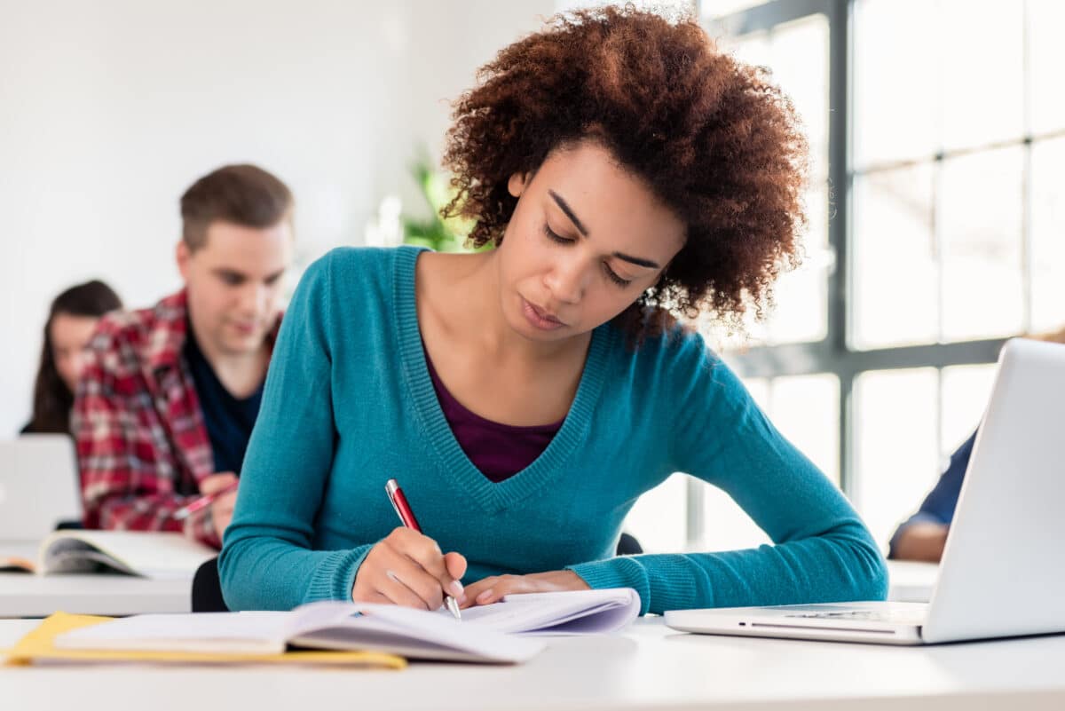 College student taking exam and writing in notebook