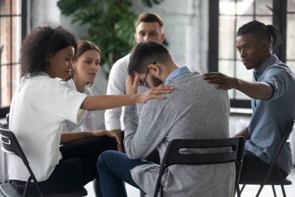 Group of colleagues or friends comforting crying man