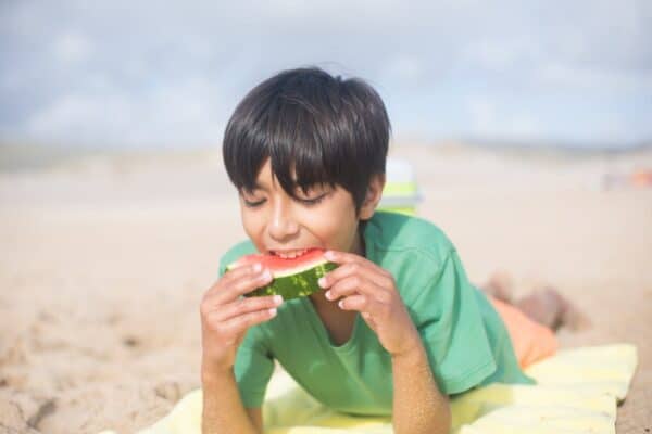 Boy eating watermelon on the beach