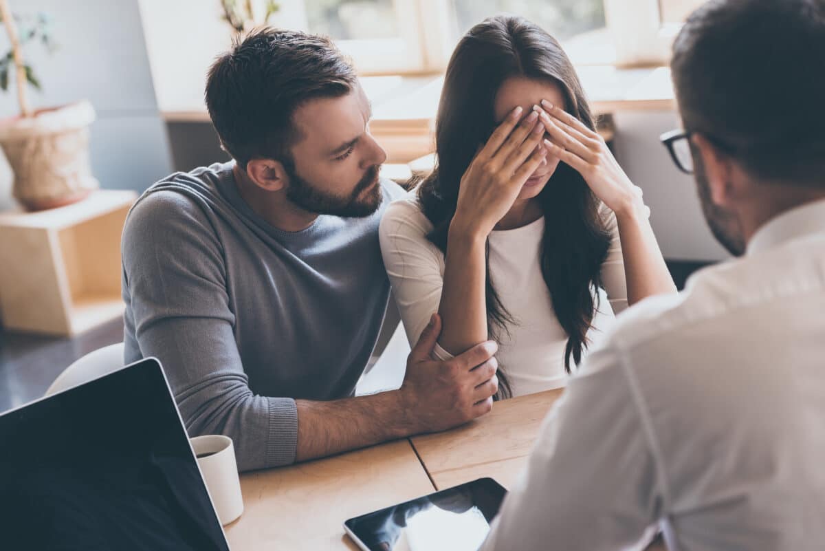 Woman comforted by her husband after receiving diagnosis from doctor