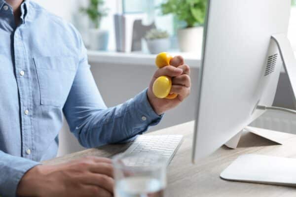 Man squeezing a stress ball while doing work at his desk
