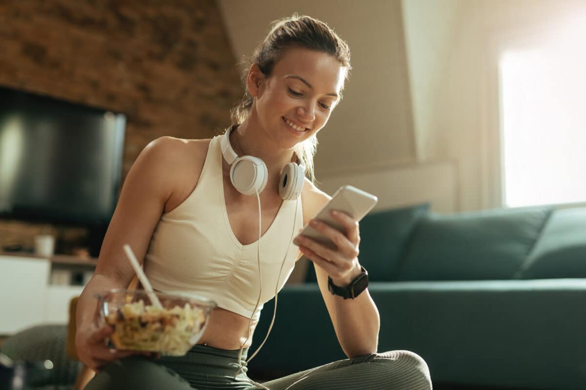 Woman having her post-exercise meal while looking at her phone