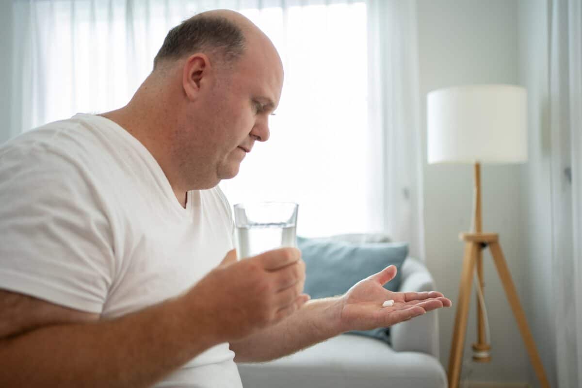 Man taking medication pills for hair loss or depression