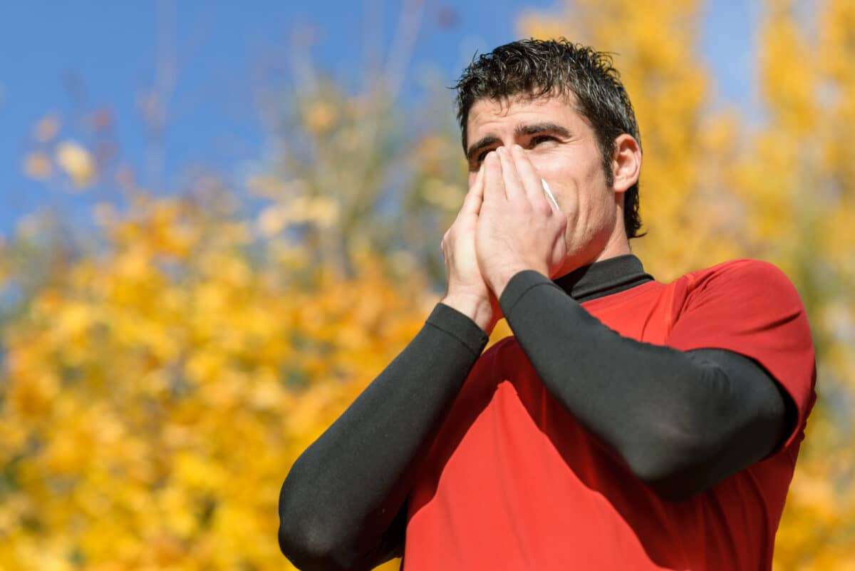 Man blowing his nose while running outside